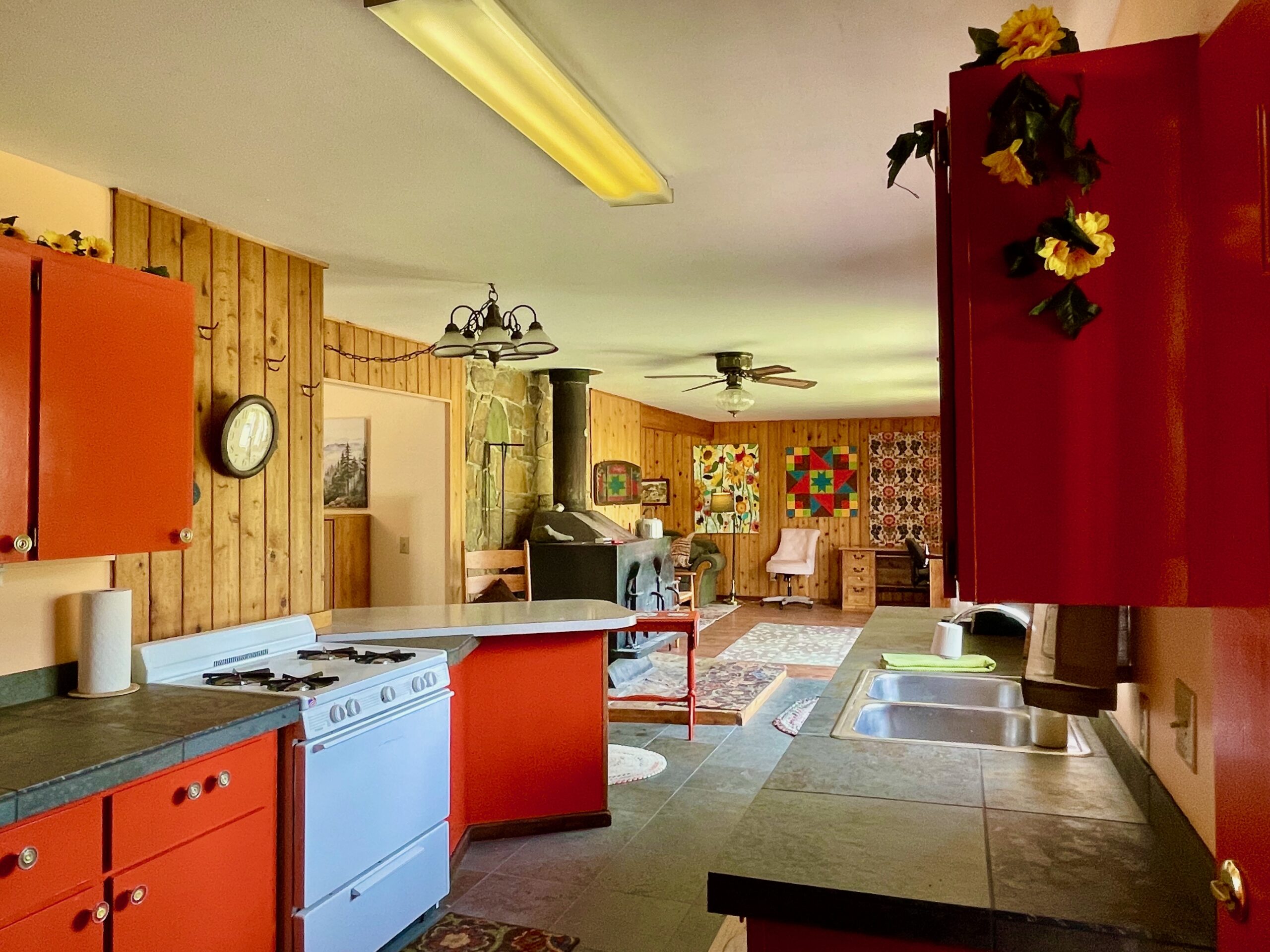 Looking from the front door and viewing the kitchen with bar, the giant wood stove with rock wall behind it and into the living room.
