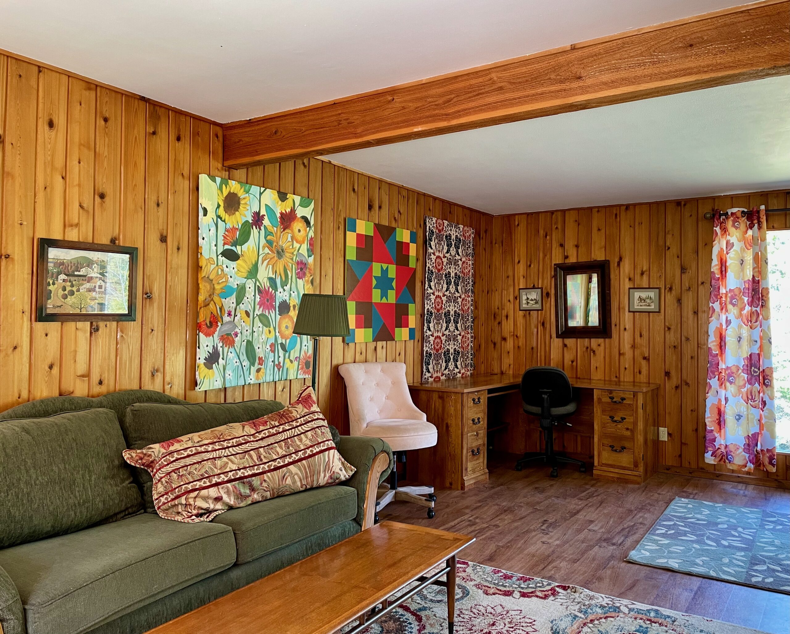 Close up of paneling and corner desk next to large front window.