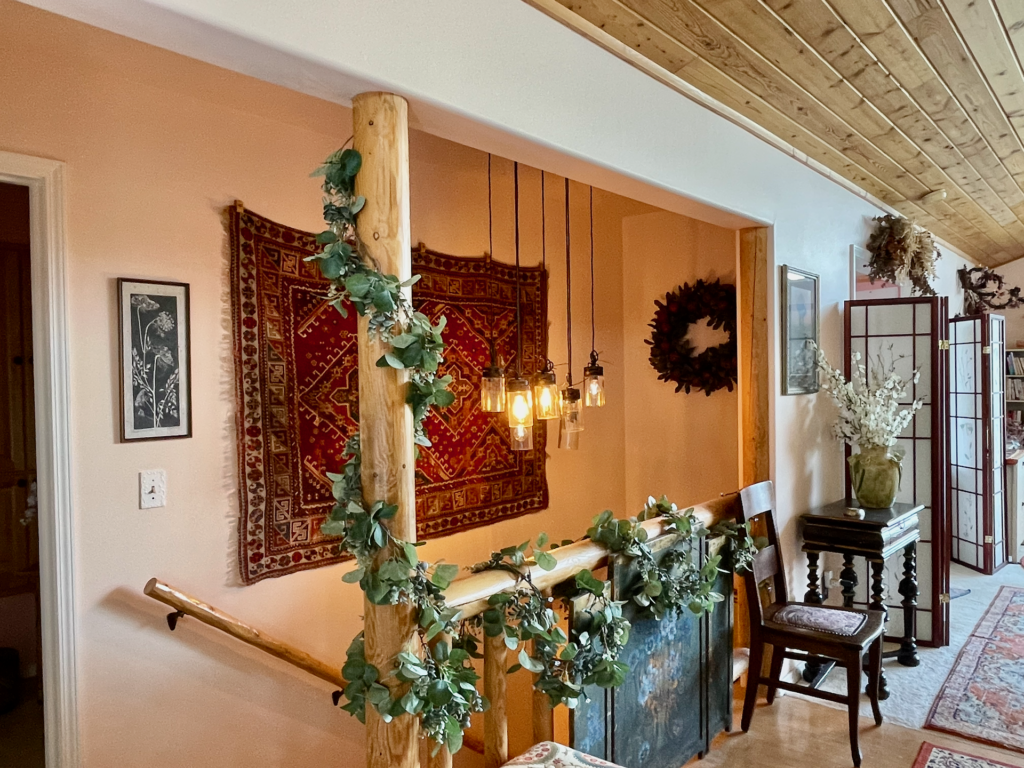 Log-pole railing leading to the basement with a multi-light hanging fixture.
