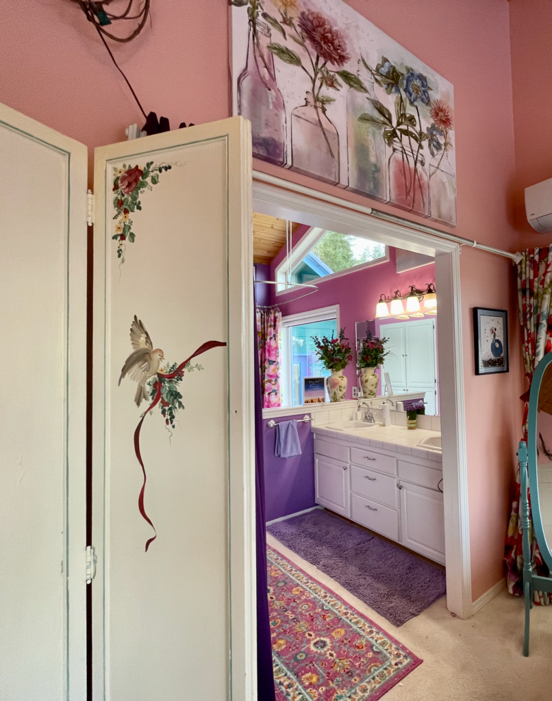 Open entrance to ensuite bath with view of white tile counters and white cabinets.