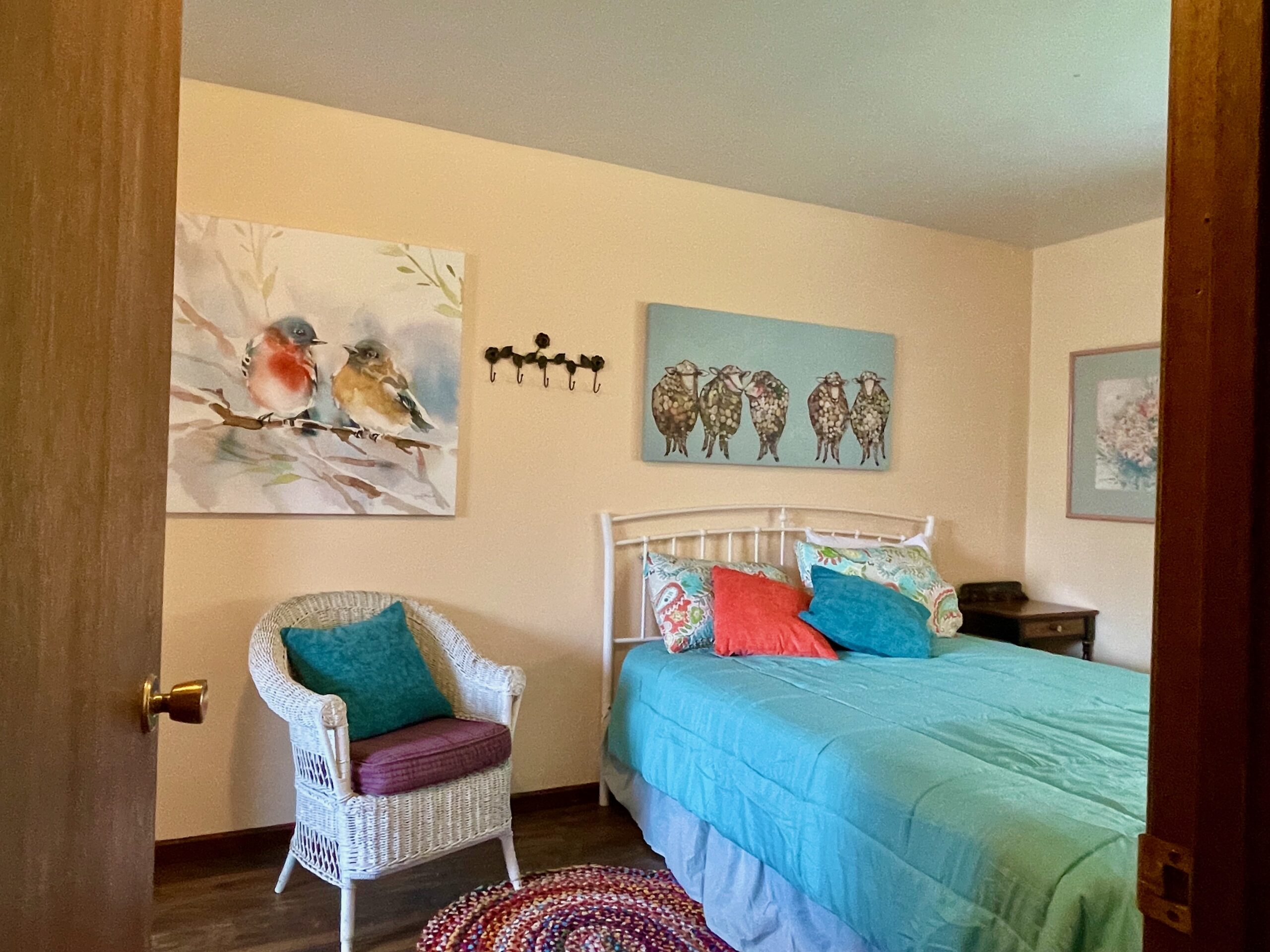 Entering the master bedroom at the top of the stairs. Walls are painted a very soft pink. Room is furnished and has a queen size metal frame bed.